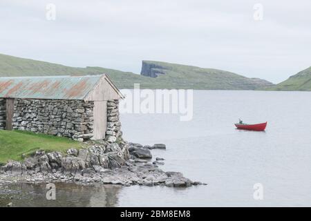 Morning view on lonely boat on cloudy Sorvagsvatn lake on cliffs of Vagar island, Faroe Islands, Denmark. Landscape photography Stock Photo