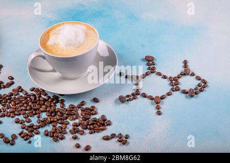 a cup of coffee with caffeine molecule created by coffee beans. Chemical formula of Caffeine with roasted coffee spill out of cup on blue wooden backg Stock Photo