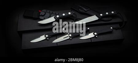 A variety of knives, penknife and hunting on a dark background. Modern knives with shiny blades. Stock Photo