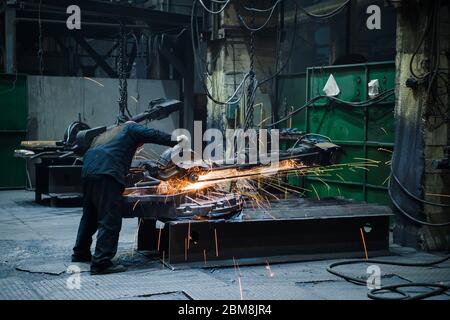 Industrial workers with work tool. Big chainsaw in hands at steel factory. Stock Photo