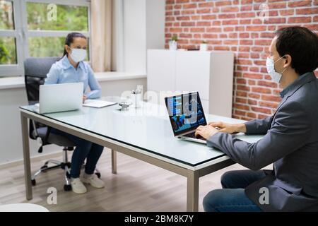 Computer Analyst Working On Laptop Wearing Face Mask Stock Photo