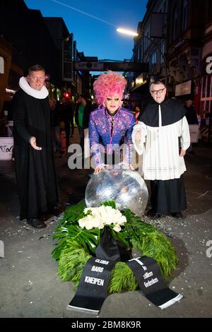 07 May 2020, Hamburg: Olivia Jones (M), drag queen and entrepreneur, Sieghard Wilm (l), pastor of the St. Pauli Church, and Karl Schultz, pastor at the St. Joseph Church, stand next to a symbolically laid down funeral wreath and a burst disco ball at a protest action of neighborhood restaurateurs, club and pub owners on Beatles Platz in front of the Große Freiheit on the Reeperbahn. In Hamburg's cult district of St. Pauli, bar and pub owners drew attention to their existential needs on Thursday evening because of the Corona crisis and demanded more financial aid. The initiator of the protest a Stock Photo