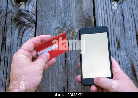two hands holding a smartphone and a bank card simulating internet shopping Stock Photo