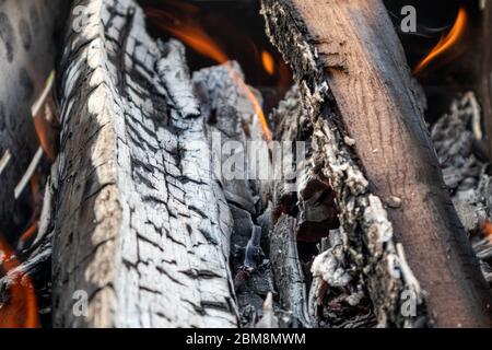 Burned wood grey coal with small hot red orange wood fire on branches burning close-up. Warm flames on charcoal Stock Photo