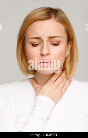 Closeup studio portrait of sick young woman suffering from throat problems. Thyroid gland, painful swallowing, tonsillitis concept. Inflammation of th