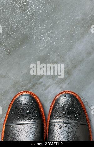 Top view of black leather men boots with water drops on grunge navy blue background, copy space, flat lay. Warm shoes for autumn weather. Stock Photo