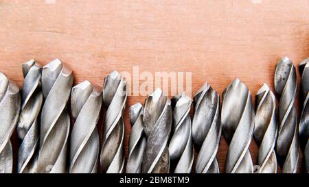 Set of old various twist drill bits with different sizes on wooden background, close up, top view, copy space. Stock Photo