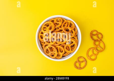 Salted pretzels in a white bowl isolated against a yellow background with copy space Stock Photo