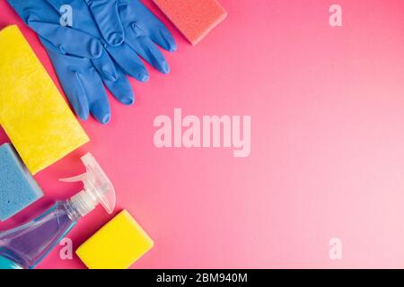 Colorful cleaning set for different surfaces in kitchen, bathroom and other rooms. Empty place for text or logo on pink background. Cleaning service Stock Photo