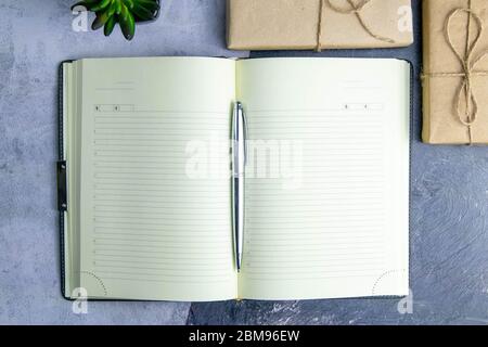 School notebook with gifts on a gray background, gift boxes with a notebook on the table. Top views with clear space Stock Photo