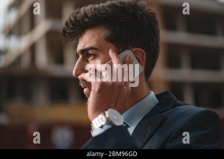 Young male construction engineer or businessman talking on phone looks at his wrist watch Civil engineer,construction Plan Stock Photo