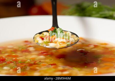 In a spoon is a vegetarian dietetic Italian soup with red lentils, small pasta - ptitim, vegetables, herbs and spices. Stock Photo