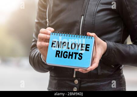 EMPLOYEE RIGHTS concept. Holding blue notebook with text. Sunny day Stock Photo