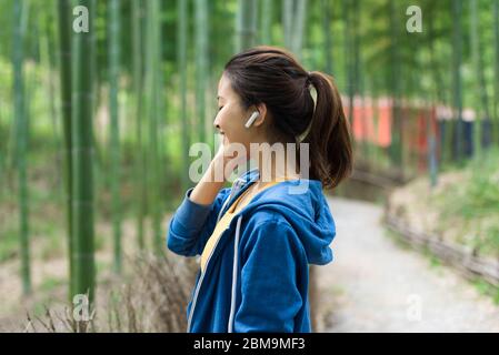 A young Asian woman walks and rests in a bamboo forest Stock Photo