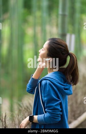 A young Asian woman walks and rests in a bamboo forest Stock Photo