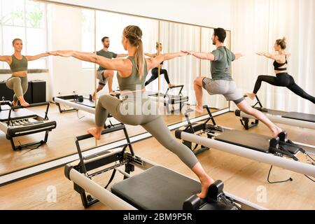 Premium Photo  Fit man performing a lunge and stretch warrior 2 yoga pose  on a pilates reformer bed to stretch and strengthen his hip and chest  muscles and promote stamina