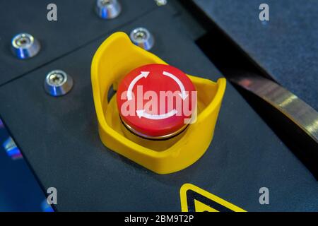 Red emergency button with arrows on black panel Stock Photo