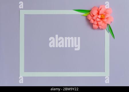 Rectangle frame with pink color paper flower on pastel violet blue background. Flat lay, copy space Stock Photo