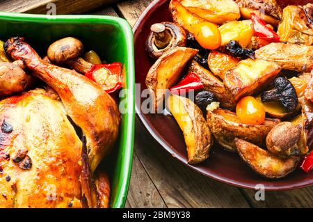 Baked chicken with apples on old wooden table.Fried chicken with apples.Tasty aromatic rotisserie chicken Stock Photo