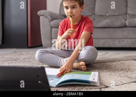 boy seating on the floor, learning at home studying remotely, preschool kids with computer, distance online education. homeschooling. Stock Photo