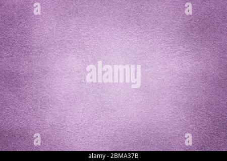 Background of light violet suede fabric closeup. Velvet matt texture of lilac nubuck textile with vignette. Stock Photo