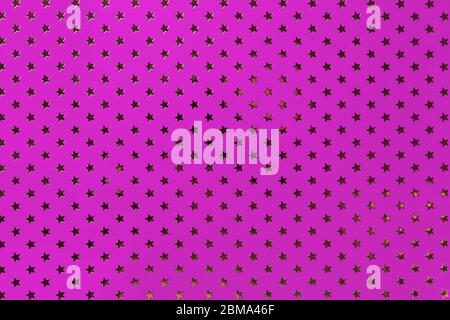 Dark purple background from metal foil paper with a pattern of sparkling golden stars, closeup. Texture of magenta metallized wrapping holiday paper s Stock Photo
