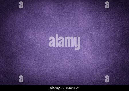 Dark violet matte background of suede fabric, closeup. Velvet texture of seamless purple leather. Felt material macro with vignette. Stock Photo