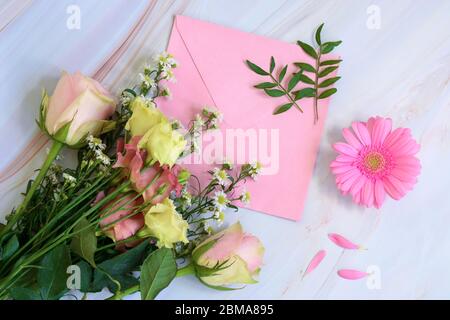 Pink floral composition with flowers, envelope and leaves on a marble background. Top view and flat lay style. Valentines day, mothers day, womens day Stock Photo