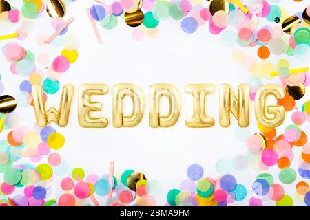 Word WEDDING made of golden inflatable balloon letters in a frame made of colorful confetti Stock Photo