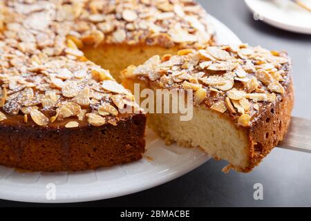 Cutting and serving a portion of almond and lemon cake with sliced almonds topping Stock Photo