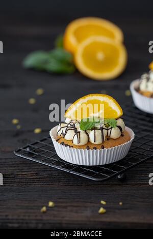Cupcake with fresh oranges, vanillacream on a dark wooden Background Stock Photo