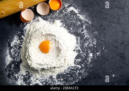 Ingredients for baking - dough, flour, rolling pin, eggs, egg yolks on a dark background. Top views with clear space Stock Photo