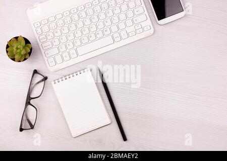 Business concept. Work from home. Office flatlay with white keyboard, reading glasses, pet and notebook. Stock Photo