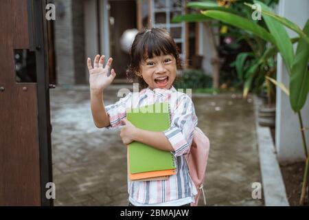 happy kid wave her hand before going to school in the morning Stock Photo