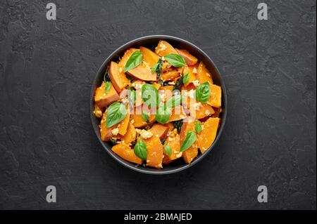 Pad Faktong or Thai Stir-fried Pumpkin in black bowl at dark slate backdrop. Pad Phuk Tong is thailand cuisine dish with sliced Kabocha Squash, eggs o Stock Photo