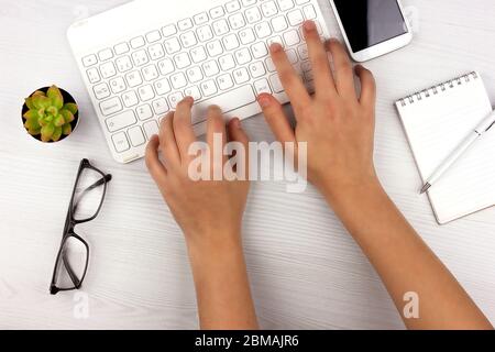Online education. Home schooling at quarantine and self isolation during coronavirus. Flat lay with white keyboard, apple, alarm clock and hands Stock Photo
