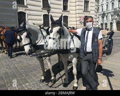 Wien, Austria. 08th May, 2020. The 53-year-old hackney carriage driver Hermann Hofer waits for customers with face masks on the Michaelerplatz in Vienna, which is otherwise crowded with tourists. The hope is that the locals will discover the charm of the carriage rides (to dpa First Fiaker are back - but business extremely bad) Credit: Matthias Röder/dpa/Alamy Live News Stock Photo