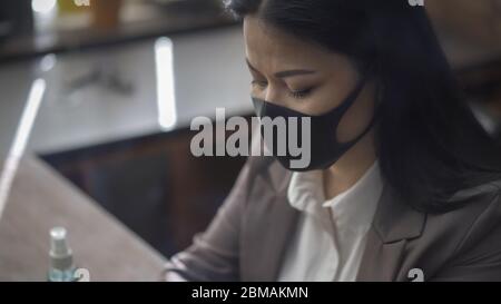 Asian woman wearing black protective mask working in office. Businesswoman smart working during coronavirus outbreak. Close up portrait Stock Photo