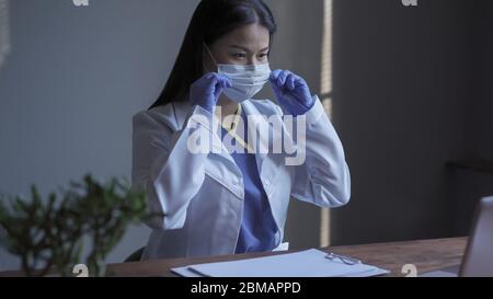 Doctor working on computer. Pretty medical worker corracts medic mask when conducting computer research in the field of medicine. Medical research Stock Photo