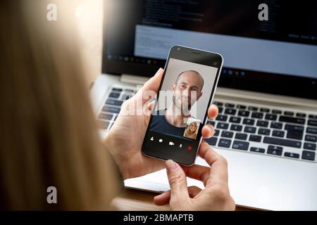 Man and woman talking to each other through a video call on her smartphone. Young blonde woman having a video chat with man on mobile phone. Stock Photo
