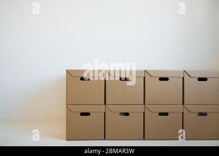Cardboard boxes for storage that are neatly stacked against a white wall. Concept of delivery. Stock Photo