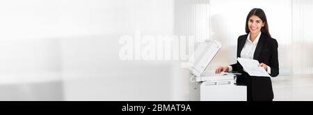 Woman Using Photocopy Machine In Office. Printer And Copier Stock Photo