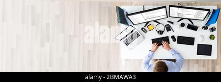 Developer Working On Multiple Computer Screens At Office Desk Stock Photo