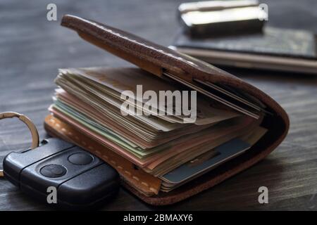 Old leather wallet full of money on wooden background, close up Stock Photo