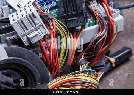 Multi-colored electrical wires with connectors in the nodes of the car during network repair by an engineer or mechanic in service or workshop. Stock Photo