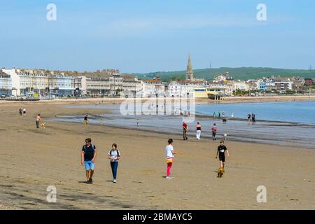 Weymouth, Dorset, UK.  8th May 2020.  UK Weather:  People exercising on the beach on a day of hot sunshine at the seaside resort of Weymouth in Dorset on the 75th anniversary of VE Day during the coronavirus lockdown.  Picture Credit: Graham Hunt/Alamy Live News Stock Photo