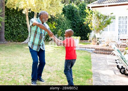 Senior African American man and his grandson spending time together in their garden on a sunny day Stock Photo