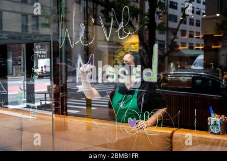 New York, USA. 8th May, 2020. A Starbucks employee wears a face mask as she paints a sign reading 'We've missed you' in the Upper East Side coffee shop window, as they reopen for take outs only after over a month of being closed due to the COVID-19 crisis. Credit: Enrique Shore/Alamy Live News Stock Photo