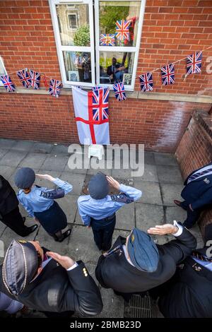 Cadets salute 95 year old Second World War veteran Signalman Eric Bradshaw, who is in isolation after testing positive for covid 19, outside Anchor's Millfield care home in Oldham, Greater Manchester, during a day of events to mark the 75th anniversary of VE Day. Stock Photo