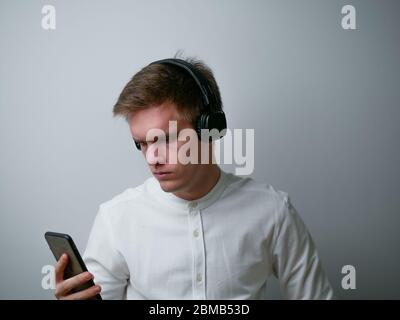 Close-up portrait of young man wearing white shirt listening pop rock stereo sound spending weekend isolated over white background. Stock Photo